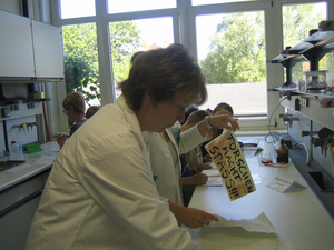 Kinder und eine Betreuerin beim Experimentieren im Labor